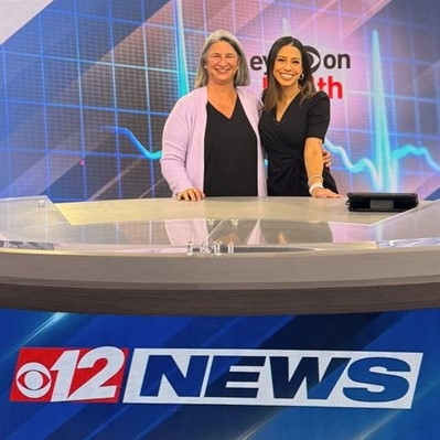 Two women standing in front of a news desk

Description automatically generated